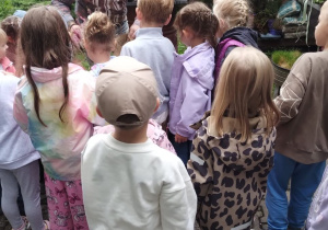 Dzieci słuchają pracownika kwiaciarni opowiadającego o roślinach