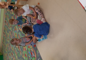Czworo dzieci bawi się klockami na podłodze.