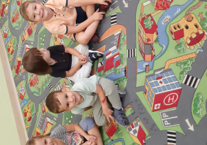 Dzieci siedzą na dywanie w kole.