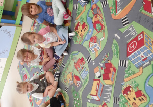 Siedzące dzieci na dywanie uczą się wiersza ,, Mam 3 latka''.