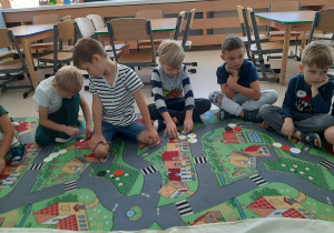 Dzieci siedzą na dywanie i układają dowolny obrazek z kropek różnej wielkości.