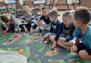 Dzieci siedzą na dywanie i układają dowolny obrazek z zebranych kropek.