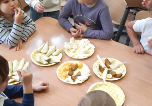 Dzieci jedzą owoce przy stoliku