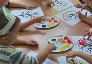 Dzieci wykonuj pracę plastyczną, stemplują sylwetę drzewa farbą