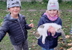 Chłopiec z dziewczynką pozują do zdjęcia, dziewczynka trzyma kota na rękach