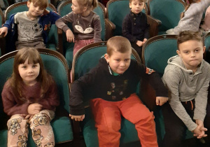 Dzieci siedzą na widowni teatru i pozują do zdjęcia