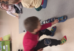 Chłopiec ustawia buta wzdłuż dywnu.