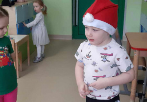 Chłopiec stoi w czapce świętego Mikołaja