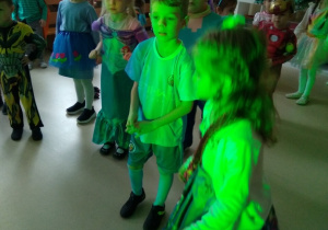 Dzieci w świetle fleszy przygotowują się do kolejnego tańca podczas balu karnawałowego.