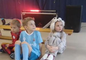 Troje dzieci przygotowuje się do konkursu sprawnościowego podczas balu karnawałowego.