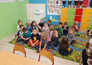 Dzieci siedzą na dywanie w klasie