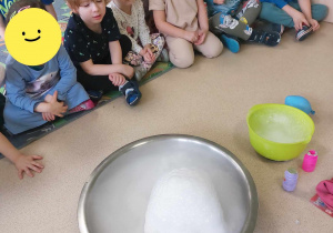 Dzieci siedzą na dywanie podczas eksperymentów z suchym lodem