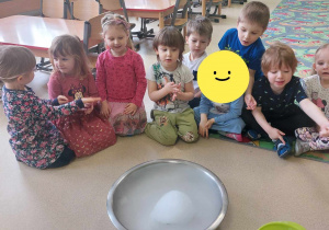 Dzieci siedzą na dywanie podczas eksperymentów z suchym lodem