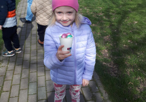 Dziewczynka pozuje do zdjęcia z kubeczkiem pełnym czekoladowych jajek