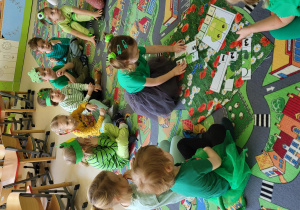 Dzieci siedzą w kole na dywanie i układają puzzle