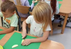 Dziewczynka i chłopiec siedzą przy stoliku i kroją jabłka.