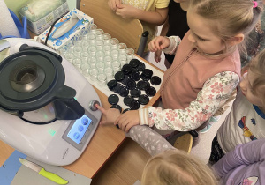Dzieci razem z wychowawcą uruchamiają thermomix