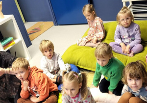 Dzieci siedzą na kolorowych poduszkach