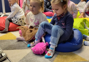 Dzieci siedzą na kolorowych poduszkach