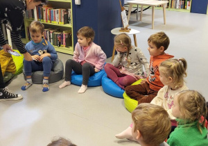 Dzieci siedzą w kole na kolorowych poduszkach