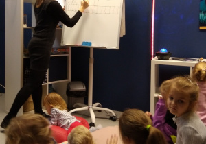 Pani bibliotekarka zapisuje w krzyżówce rozwiązania zagadek, które wskazują jej dzieci.