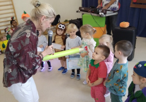 Pani Dyrektor wskazuje dużym ołówkiem nowego przedszkolaka.