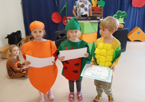 Troje dzieci pozuje do zdjęcia, trzymając w rękach dyplom przedszkolaka