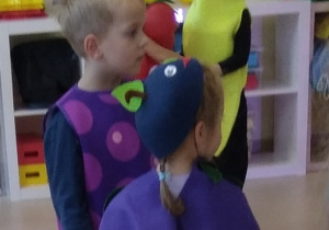 Dziewczynka z chłopcem przebrani za jesienne owoce rozpoczynają wspólny taniec.