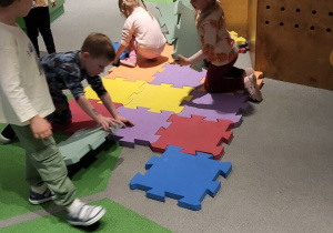Dzieci układają duże, piankowe puzzle.