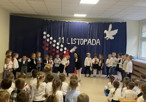 Dzieci śpiewają i tańczą na scenie.