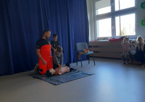 Chłopiec wykonuje uciśnięcia klatki piersiowej na fantomie.