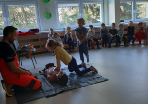 Dziewczynka wykonuje uciśnięcia na klatkę piersiową na fantomie