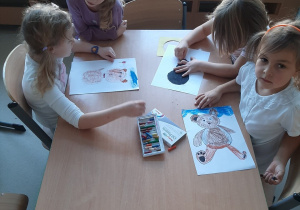 Dziewczynki siedzą przy stoliku i rysują misie.