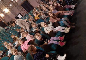 Dzieci zajmują miejsca na sali widowiskowej w Teatrze.