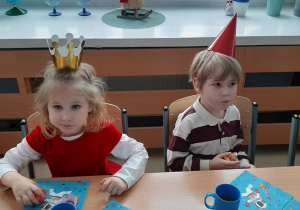 Dwoje dzieci siedzi przy stole i je słodycze.