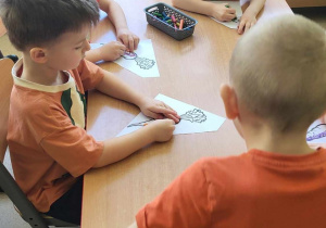 Dzieci kolorują sylwetę marchewki.
