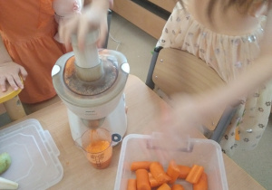 Dziewczynka wyciska sok z marchewki.