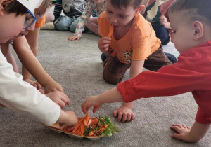 Dzieci degustują marchewkę.