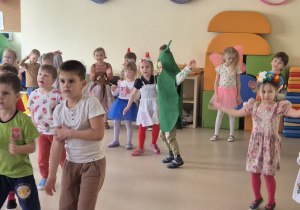 Tańcząca grupa dzieci w strojach o tematyce wiosennej.