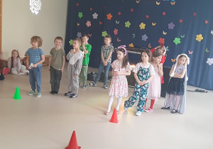 Dzieci ustawione w dwóch rzędach przed pachołkami czekają na rozpoczęcie zabawy sportowej
