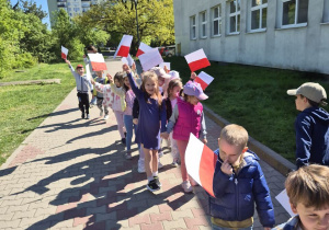 Dzieci idą w pochodzie z flagami