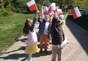 Dzieci idą z biało-czerwonymi flagami