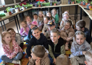Dzieci oglądają film edukacyjny o przesadzaniu kwiatów.