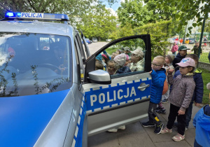 Dzieci oglądają policyjny radiowóz.
