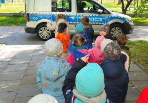 Dzieci stoją w kolejce, aby oglądać radiowóz.