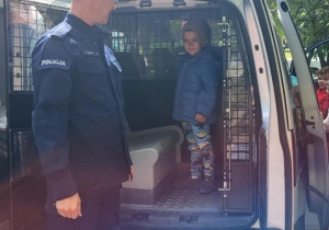 Chłopiec stoi w samochodzie policyjnym.