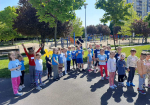 Dzieci stoją na boisku i czekają na rozpoczęcie maratonu sportowego.