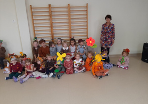 Dzieci przebrane w stroje jesienne siedzą na sali gimnastycznej