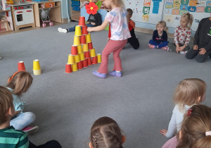 Dziewczynka kładzie chrupki dla psa na papierowych kubeczkach.