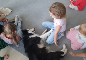 Pies leży między dziećmi.